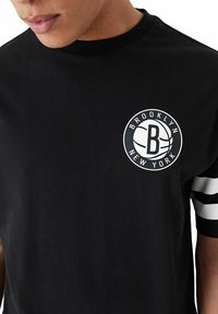 Schwarzes Baumwoll-T-Shirt mit Rundhalsausschnitt, das ein weißes kreisförmiges Grafikdesign mit dem Text "Brooklyn New York" und einem Basketball-Design sowie gestreiften Ärmeln zeigt.