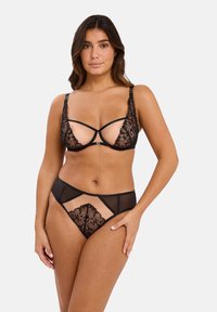 Ensemble de lingerie en dentelle noire avec des détails floraux, des panneaux en mesh transparent, des bretelles réglables et une coupe moderne avec une taille basse.
