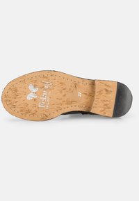 Semelle de chaussure noire avec une base en liège naturel, une texture rugueuse et un embout en caoutchouc. "Falling in love" imprimé sur le liège avec la taille 37 indiquée.