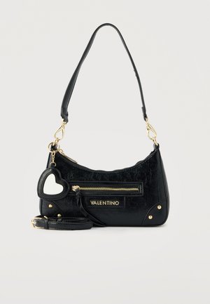 Μαύρη τσάντα Valentino με χρυστό φερμουάρ, πλακέτα με το λογότυπο, γούρι καθρεφτάκι σε σχήμα καρδιάς και αποσπώμενο λουρί σε ανοιχτό φόντο.