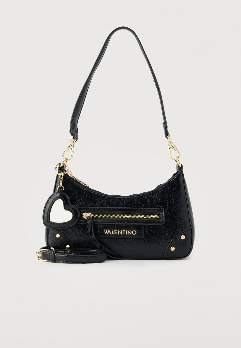 Μαύρη τσάντα Valentino με χρυστό φερμουάρ, πλακέτα με το λογότυπο, γούρι καθρεφτάκι σε σχήμα καρδιάς και αποσπώμενο λουρί σε ανοιχτό φόντο.