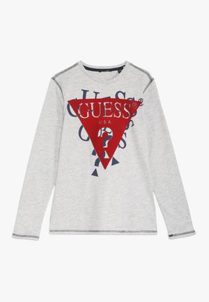 Camiseta de manga larga en gris claro con un gran logo triangular rojo de GUESS y un diseño de texto azul en el frente, que incluye un símbolo de signo de interrogación.