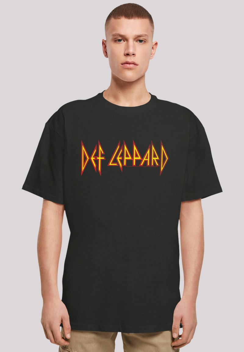 Schwarzes Baumwoll-T-Shirt mit einem auffälligen orange- und gelbfarbenen "Def Leppard"-Logo in einer gezackten Schriftart. Lockere, entspannte Passform mit kurzen Ärmeln.