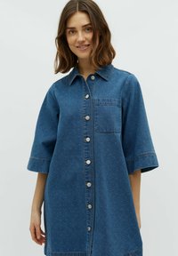 Denimhemdkleid in Dunkelblau mit kurzen Ärmeln, durchgehender Knopfleiste, Brusttasche und subtil strukturiertem Muster.