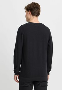 Pulover negru tricotat cu mâneci lungi și un model texturat. Mâneci și tiv cu nervuri, decolteu rotund și o croială lejeră.