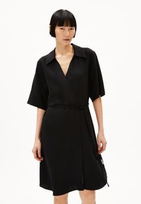 Vestito avvolgente nero con maniche corte, colletto e cintura in vita. Presenta uno scollo a V e uno spacco laterale, realizzato in un tessuto morbido.