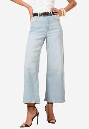 Light blue wide-leg jeans made of denim fabric, featuring a high waistband, two front pockets, and a frayed hem paired with black heels.