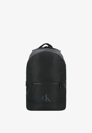 Zaino nero Calvin Klein con tasca frontale con cerniera e maniglia superiore, mostrato su sfondo bianco.