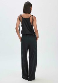 Zwarte mouwloze top met verstelbare strikbanden en wijde broek. Gemaakt van zachte stof, met een ontspannen pasvorm en zonder zichtbare patronen.
