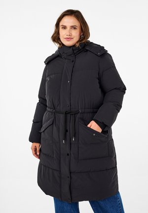 Manteau en duvet noir avec un col haut, devant à boutons, taille avec cordon de serrage et deux poches avant. Présente un design matelassé et une coupe ample.