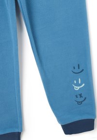 Blue fleece sweatpants with a soft texture, featuring three printed smiley faces in varying colors on the left leg and a dark navy cuff.