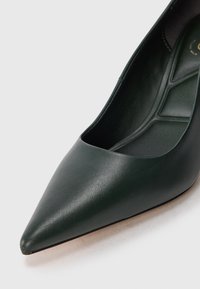 Scarpa verde in pelle a punta con texture liscia e design a ritaglio sul lato, dotata di soletta imbottita per il comfort.