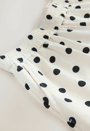 Material alb cu buline negre și talie elastică, prezentând o textură adunată și o cusătură laterală.