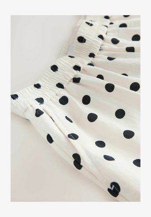 Material alb cu buline negre și talie elastică, prezentând o textură adunată și o cusătură laterală.