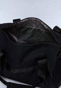 Černá taška sportovního typu z látky se zipem nahoře. Vnitřek je vybaven lesklou podšívkou a síťovanou kapsou. Pevný design a odolné popruhy.