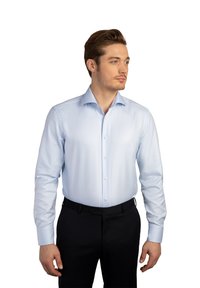 Helles blauen Hemd mit langen Ärmeln, Knopfleiste, breitem Kragen und dezenten vertikalen Streifen. Getragen mit dunklen Hosen.