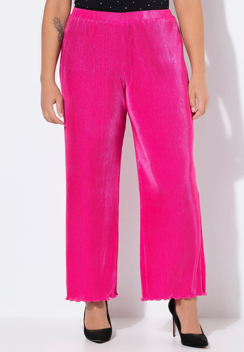 Pantalones de pierna ancha fucsias en suave tela acanalada con un dobladillo ondulado, combinados con zapatos de tacón negros. Cintura elástica visible.