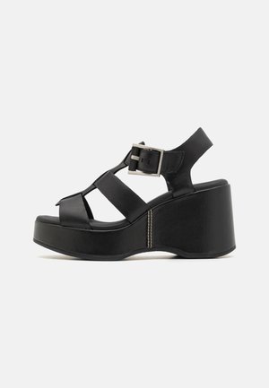 Black platform sandals with a wide strap design, buckle closure, and a smooth leather texture. Features a contoured wedge heel.