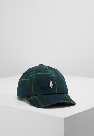 Gorra de béisbol de cuadros verdes oscuros con visera curva y logo blanco bordado de un jugador de polo en la parte frontal, colocada sobre un pedestal blanco.