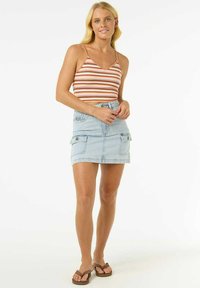 Top court rayé rouge et orange avec des bretelles fines, associé à une jupe en denim bleu clair avec des poches cargo à l'avant.