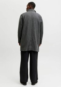 Grijze wollen jas met een hoge kraag, rechte snit en knoopmanchetten, gecombineerd met brede zwarte broek en een gemêleerde stofafwerking.