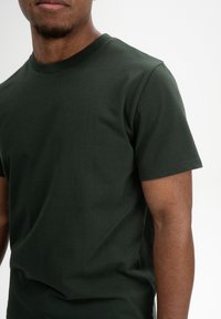 Donkergroene T-shirt met korte mouwen van zachte katoen. Heeft een klassieke ronde hals en een soepele textuur, zonder zichtbare ontwerpen.