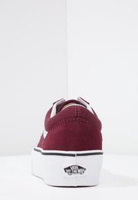 Sneakers Vans color bordeaux con tomaia in suede, dettagli bianchi, suola spessa bianca e etichetta del logo nera sul tallone. Vista posteriore che mette in risalto la texture.