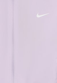 Chaqueta con cremallera de color púrpura claro, fabricada en un tejido suave, con el logo blanco de Nike en la parte superior izquierda y un bolsillo lateral.