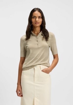 Beige poloshirt met korte mouwen, voorzien van een kraag en drie knopen, gecombineerd met een crèmekleurige rok met zijzakken en een split aan de voorkant.