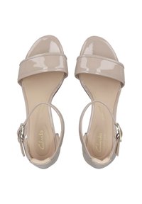 Beige patento nahka sandaalit leveillä nauhoilla, avoimella varpaalla ja säädettävällä nilkkaketjulla. Pehmustettu pohja mukavuutta varten.