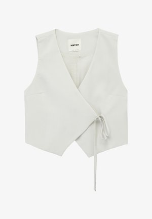 Gilet sans manches blanc croisé avec un col en V profond, noué avec un cordon fin sur le côté droit, avec une étiquette de la marque Koton à l'intérieur.