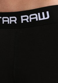 Boxer briefs neri con una larga vita elastica che presenta il logo "G-Star RAW" in bianco. Texture liscia e design aderente per il comfort.