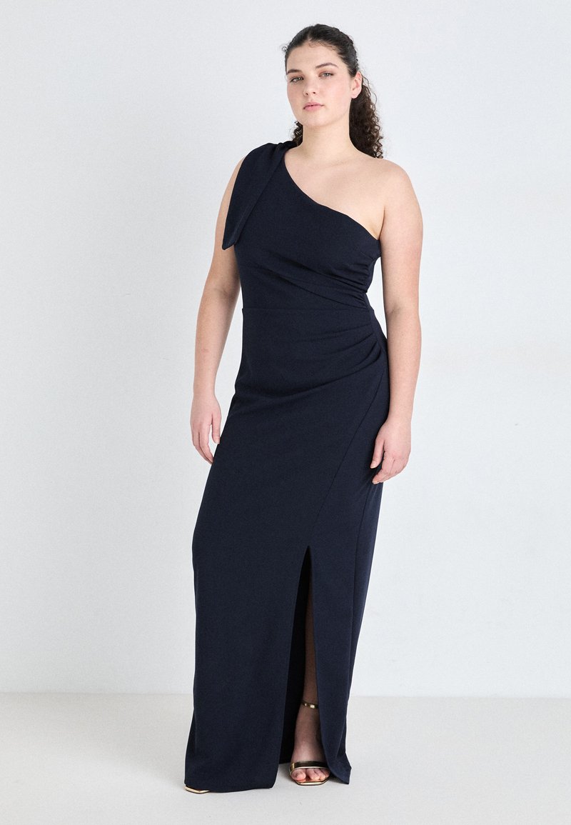 Navy blue, one-shoulder dress with a draped design, thigh-high slit, and soft fabric. Accented with a knot on the shoulder.