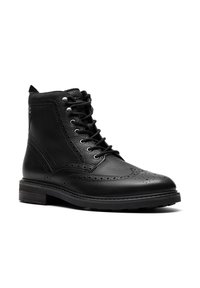Černá kožená kotníková bota s šněrovacím designem, dekorativním brogue zdobením, texturovaným povrchem a pevným gumovým podpatkem.
