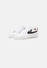 Hvite lerrets sneakers med svart akcentstripe, rund tå, teksturert gummisåle og flate snørebånd. Minimalistisk design med subtile detaljer.