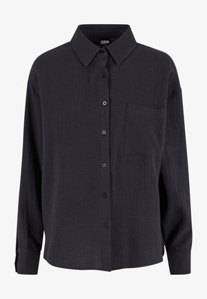 Schwarzes strukturiertes Hemd mit Kragen, langen Ärmeln, einer einzelnen Brusttasche und einer lässigen Passform. Mit subtiler knitteriger Struktur.
