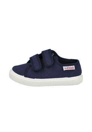 Zapatillas de lona azul marino con suelas de goma blanca, que cuentan con dos correas ajustables de velcro, puntera redonda y una etiqueta de logo rojo en el lado.