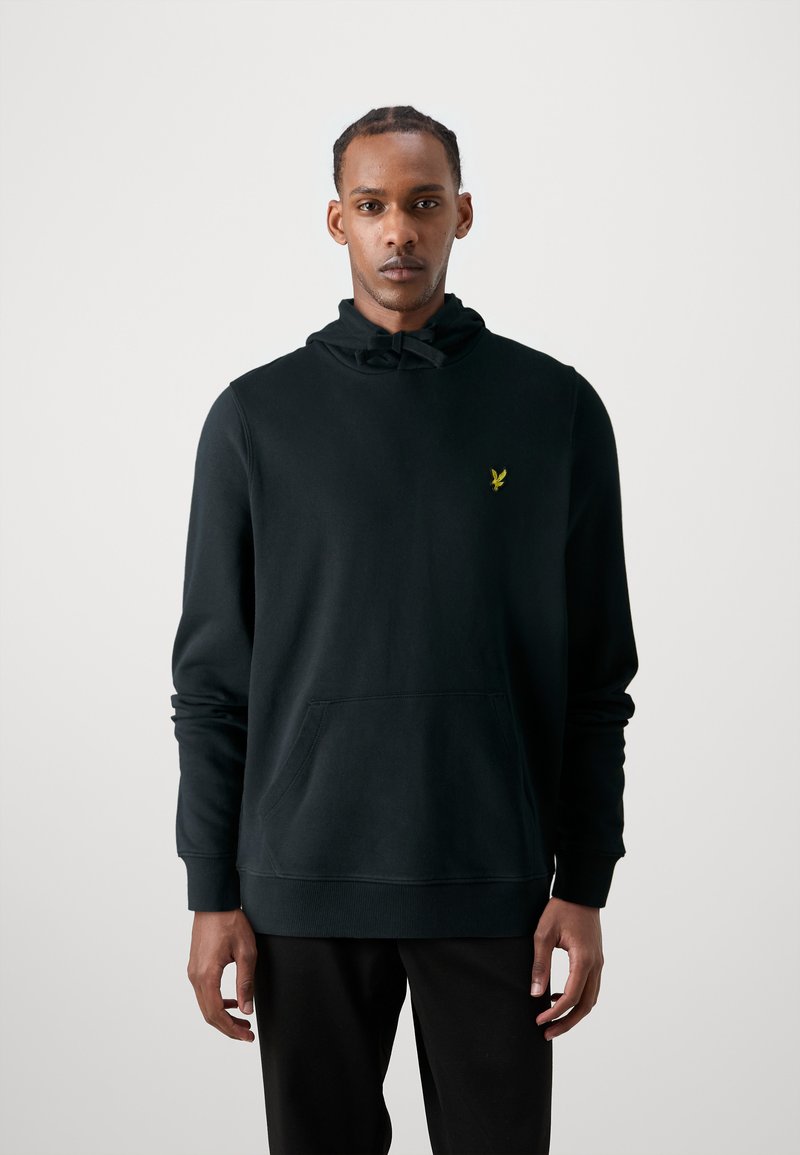Zwarte hoodie met een kangoeroezak, ribbelmanchetten en een klein geel embleem op de borst. Zachte stof met een gladde textuur.