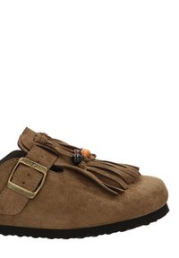 Zapato de ante marrón con punta redondeada, hebilla ajustable, flecos y cuentas decorativas. Suela de goma negra con un patrón texturizado.