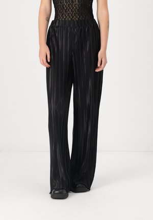 Pantalons plissés noirs avec un design à jambes larges, présentant une surface texturée et une taille élastique pour le confort.