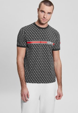 Schwarzes T-Shirt mit kurzen Ärmeln und einem sich wiederholenden Logo-Muster, ausgestattet mit einem roten und weißen Horizontalstreifen, auf dem "GUESS"-Branding über der Brust.