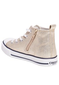 Deportivas altas en material sintético dorado con un cierre lateral, cordones blancos y una suela de goma blanca que presenta una raya y un logo azul.