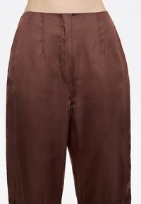 Bruine, hoog-getailleerde broek van soepelweefsel, met een losse pasvorm, subtiele glans en voorzakken met rechte naden.