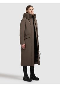 Geacă lungă matlasată maro cu guler înalt, buzunare laterale și siluetă elegantă. Materialul pare neted, cu un finisaj mat.