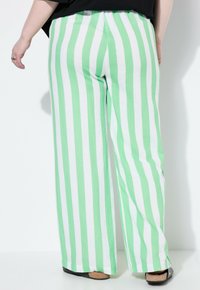 Randy och vita randiga vida byxor med bomullstextur, med hög midja och lös passform, tillsammans med svarta skor.