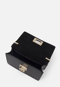 Borsa in pelle nera con una finitura testurizzata, hardware dorato e forma rettangolare. L'interno è foderato in tessuto nero e presenta una chiusura magnetica.