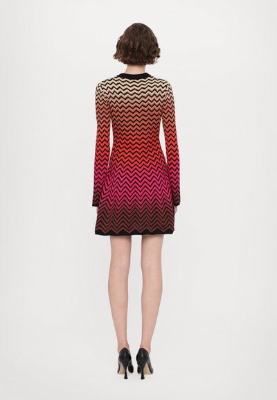 Vestido de mangas longas com um padrão em zigzag em cores degradê que vão do creme ao vermelho, terminando em preto. Feito de um tecido macio e elástico.