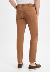 Slim-fit, bruine katoenen broeken met een gladde textuur, voorzien van achterzakken en een subtiele merklabel aan de tailleband.