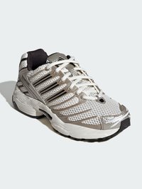 Sportowy sneaker z siateczkową cholewką, metalicznymi akcentami i czarnymi sznurowadłami. Posiada amortyzowaną podeszwę i teksturowany wzór po boku.