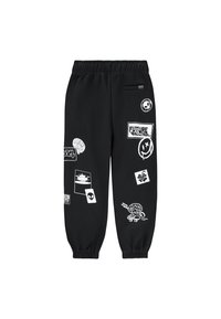 Pantalons de survêtement noirs avec une taille élastique et des poignets, ornés de divers motifs imprimés blancs, y compris des logos et des accents graphiques.